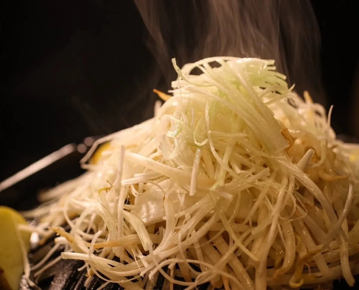 名物・大雪野菜盛り。千切りのねぎを雪山のように盛りつけた一品｜狸九